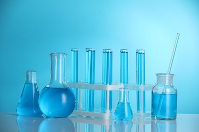 Photo of Laboratory glassware with liquid on mirror surface against blue background