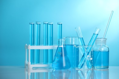 Photo of Laboratory glassware with liquid on mirror surface against blue background