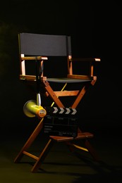 Photo of Director's chair with clapperboard and megaphone on black background