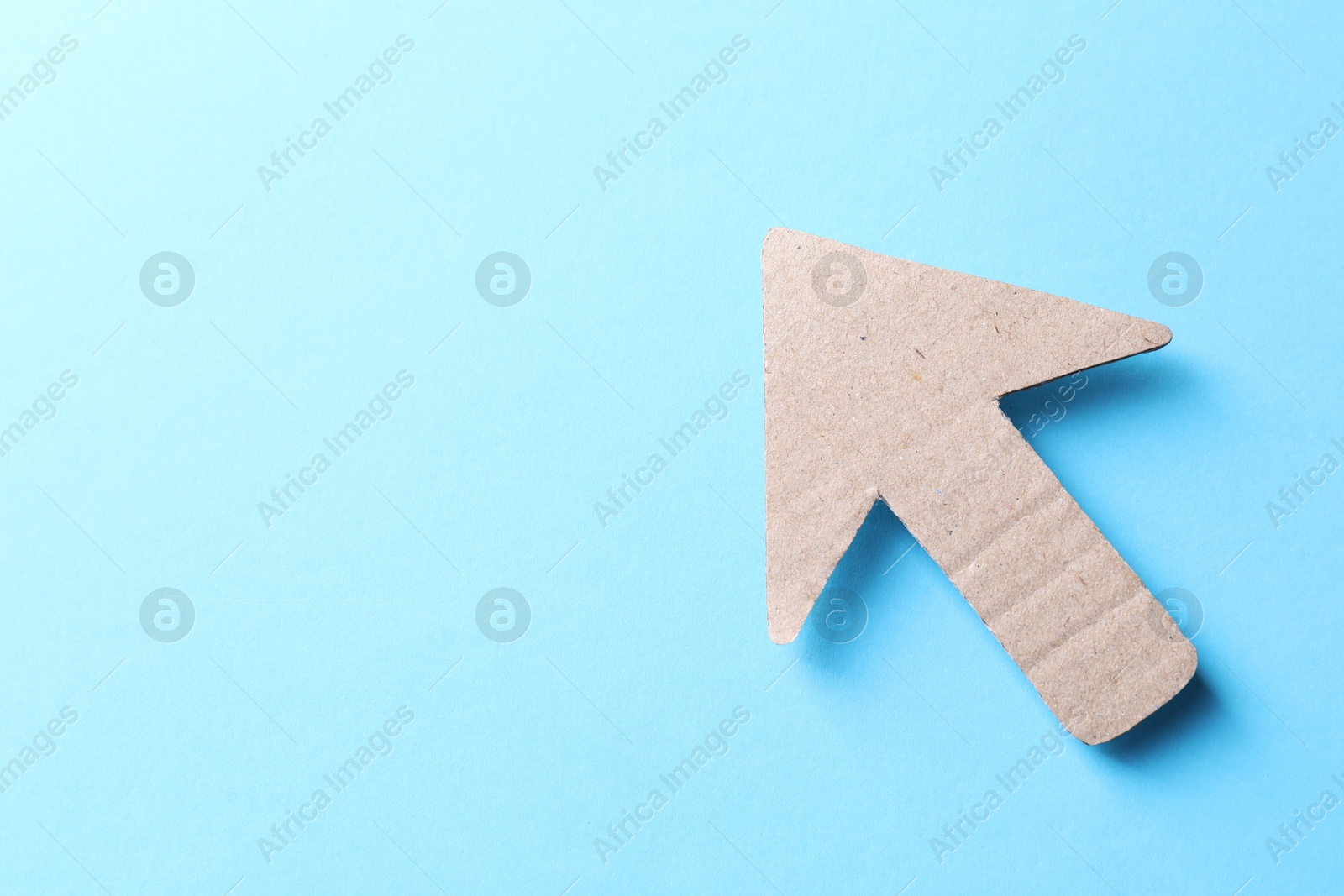 Photo of One kraft paper arrow on light blue background, top view. Space for text