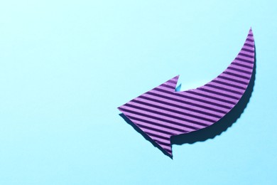 Photo of One purple paper arrow on light blue background, top view. Space for text