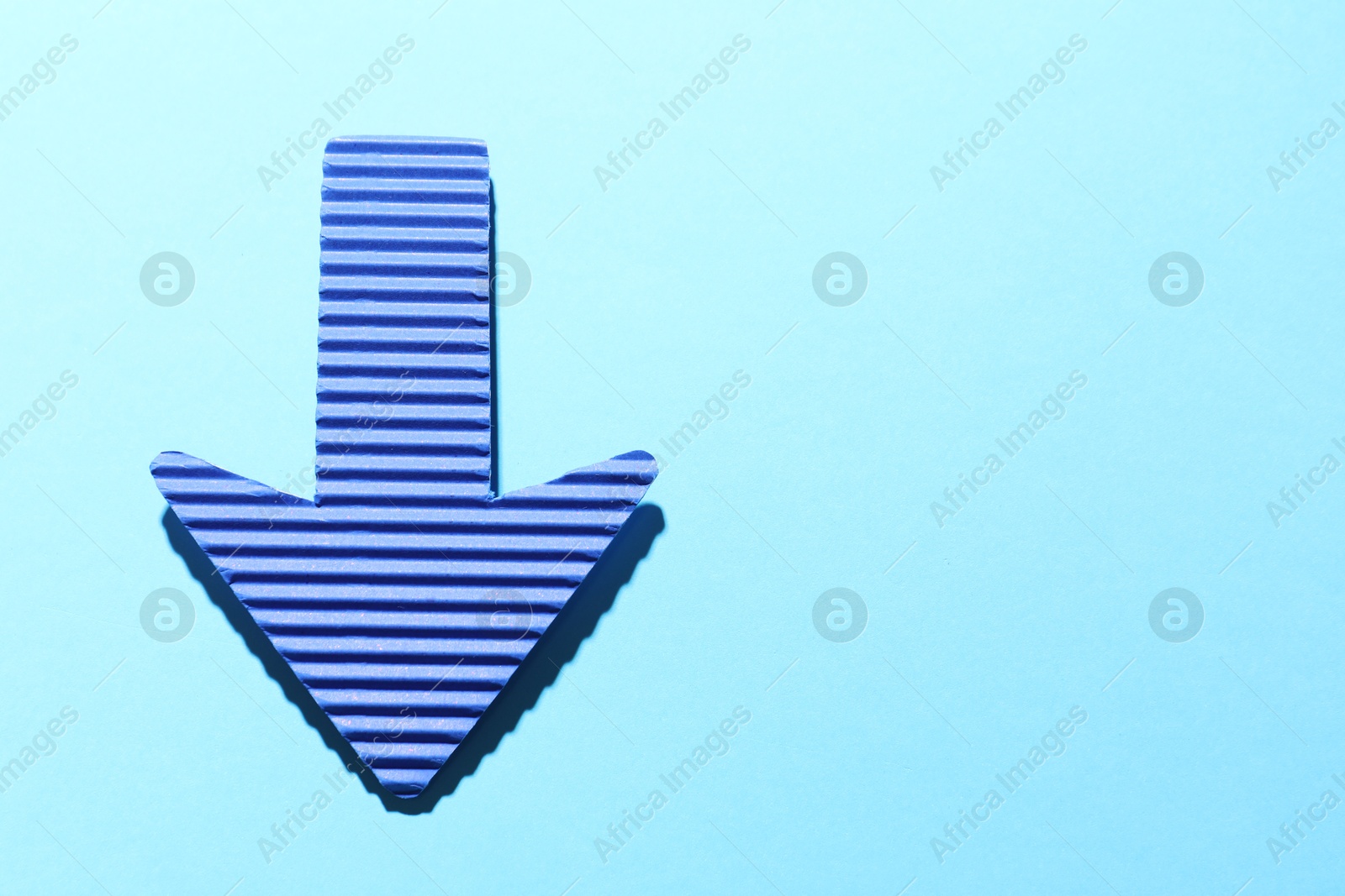 Photo of One paper arrow on light blue background, top view. Space for text