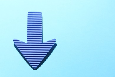 Photo of One paper arrow on light blue background, top view. Space for text