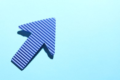 Photo of One paper arrow on light blue background, top view. Space for text