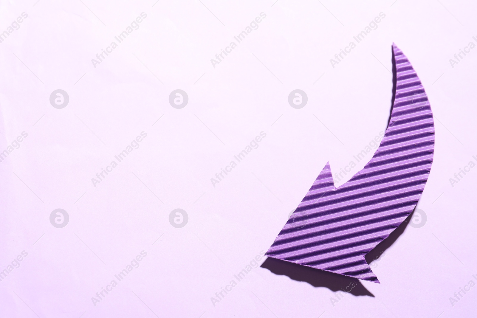 Photo of One purple paper arrow on light pink background, top view. Space for text