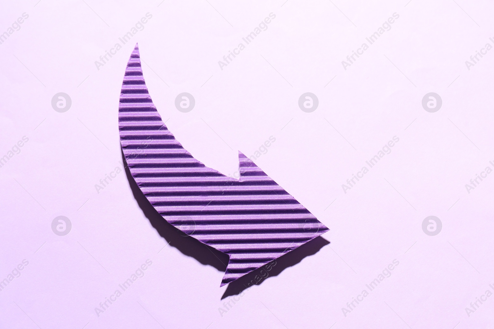 Photo of One purple paper arrow on light pink background, top view. Space for text