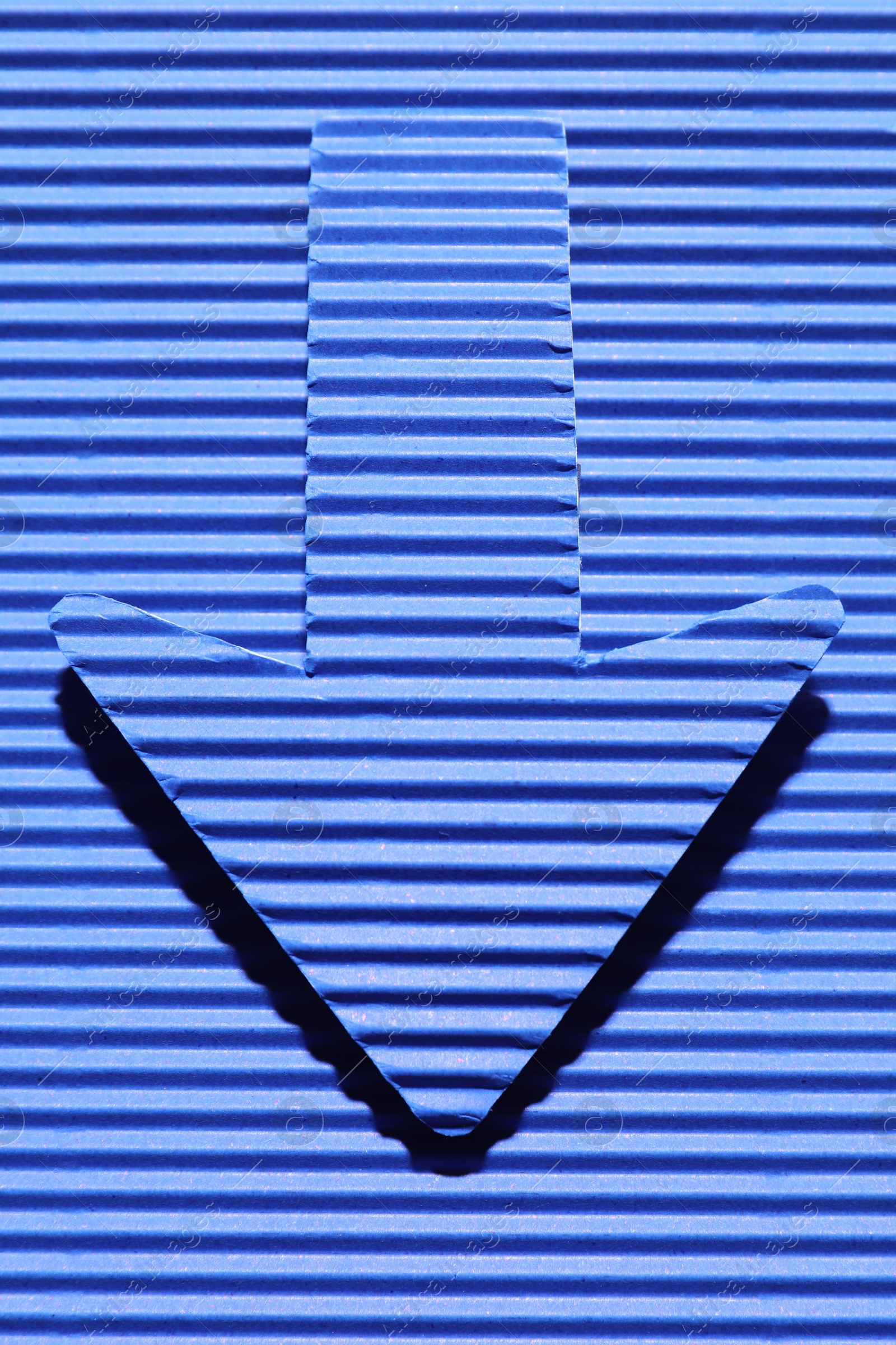 Photo of One paper arrow on blue background, top view