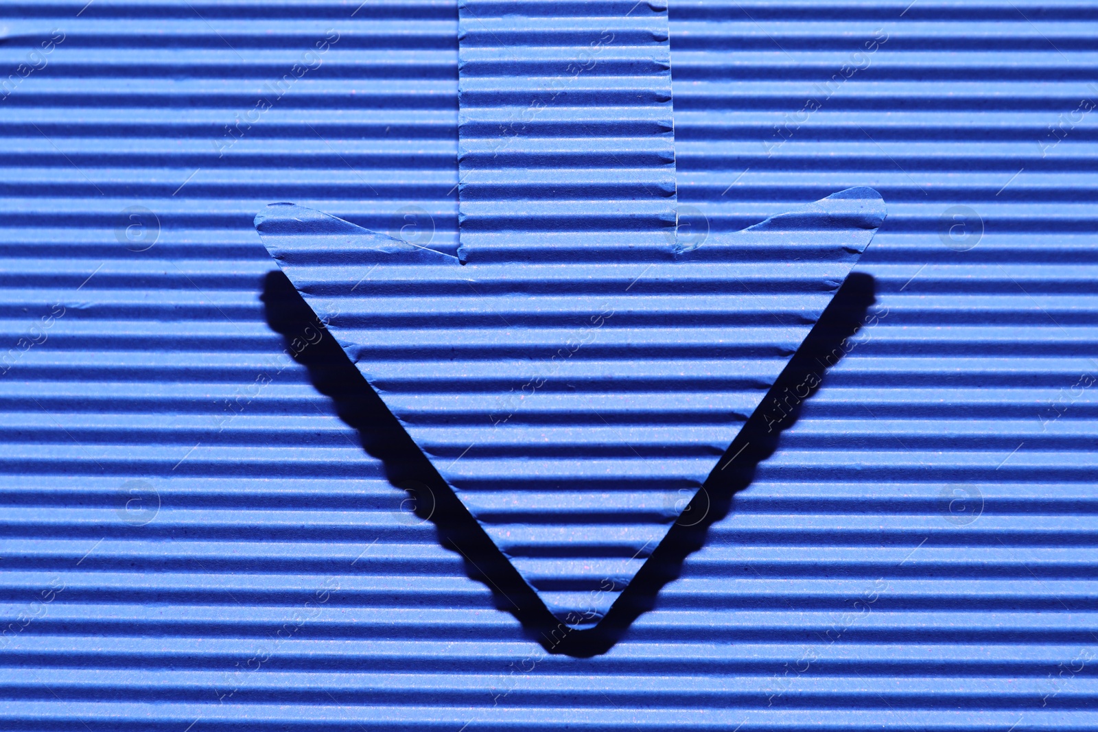 Photo of One paper arrow on blue background, top view