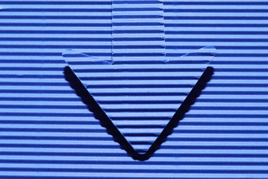 Photo of One paper arrow on blue background, top view