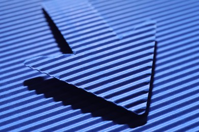 Photo of One paper arrow on blue background, closeup