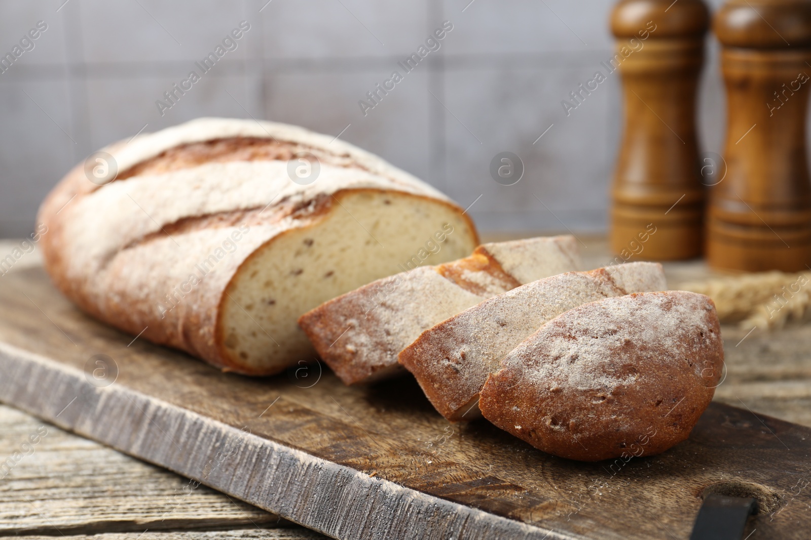 Photo of Cutting board with fresh bread on wooden table, closeup