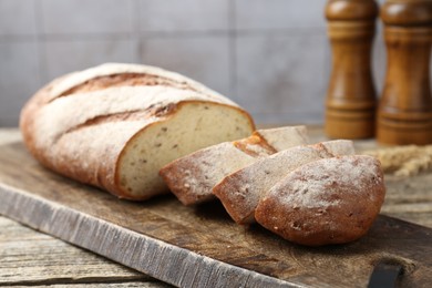 Photo of Cutting board with fresh bread on wooden table, closeup