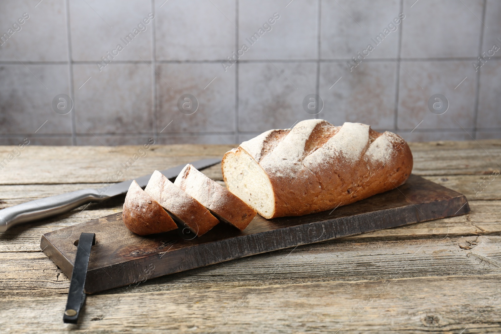 Photo of Cutting board with fresh bread and knife on wooden table