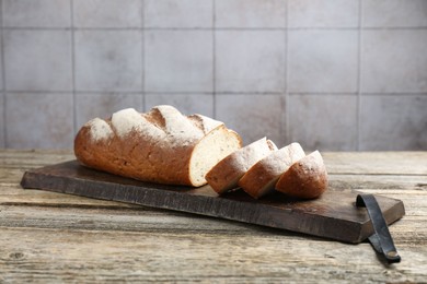 Photo of Cutting board with fresh bread on wooden table