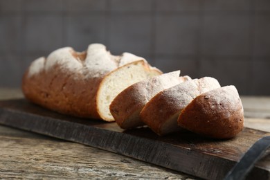 Photo of Cutting board with fresh bread on wooden table, closeup