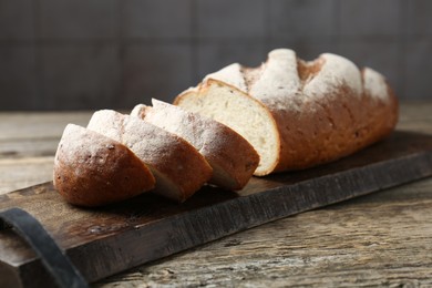 Photo of Cutting board with fresh bread on wooden table, closeup