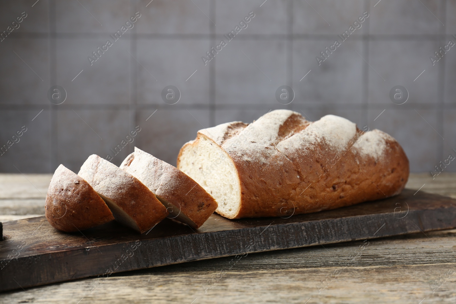 Photo of Cutting board with fresh bread on wooden table, closeup