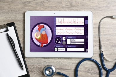 Image of Cardiology. Doctor's workplace with stethoscope and tablet computer on wooden table, top view. Data on device screen