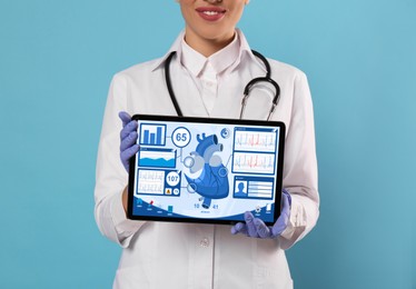 Image of Cardiology. Doctor holding tablet computer with data on screen against light blue background, closeup