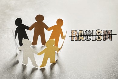 Image of Stop racism. Paper people in different colors holding hands and strikethrough word on light background