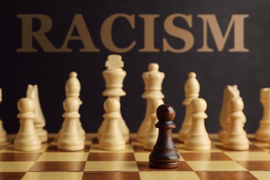 Image of Stop racism. Black pawn standing in front of white game pieces on chessboard