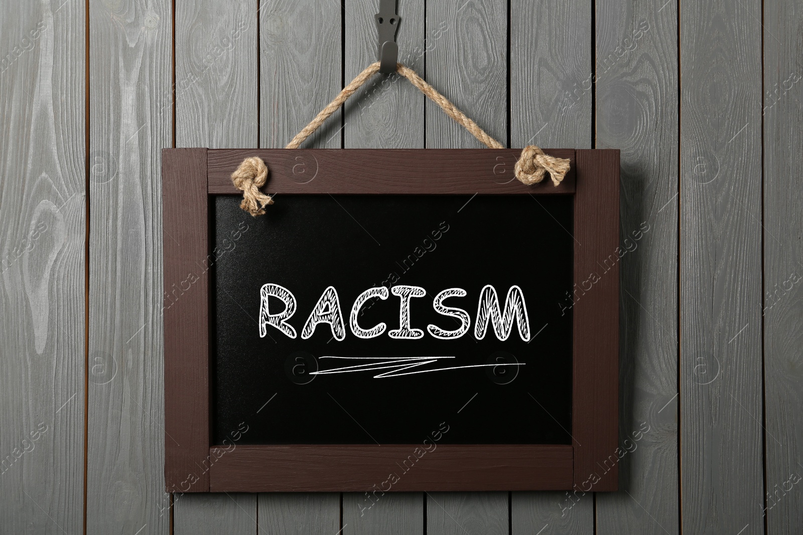 Image of Stop racism concept. Small chalkboard with word hanging on grey wooden wall