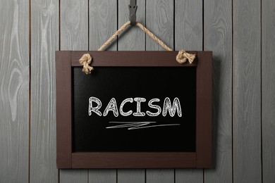 Image of Stop racism concept. Small chalkboard with word hanging on grey wooden wall