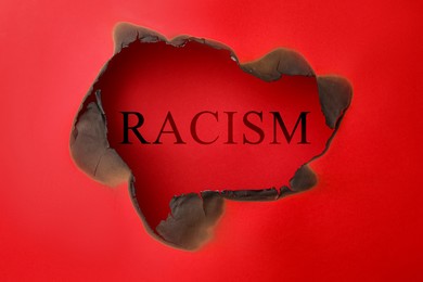 Image of Stop racism concept. View on word through burnt red paper