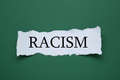 Image of Stop racism concept. Torn piece of paper with word on green background, top view