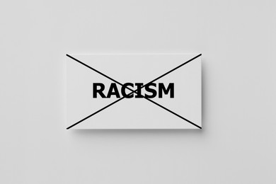 Image of Stop racism concept. Note with crossed-out word on white background, top view