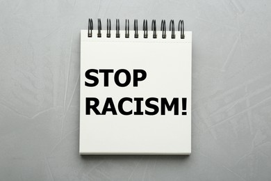 Image of Stop racism. Notebook with text on grey textured background, top view