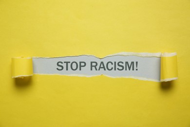 Image of Stop racism. View on text through torn yellow paper