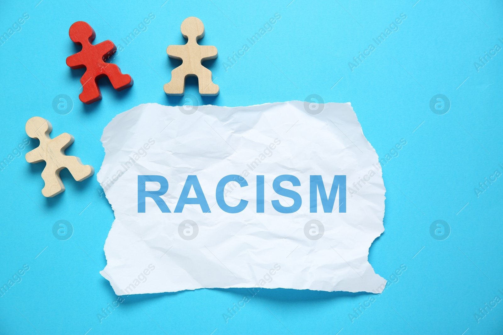 Image of Stop racism concept. Wooden men in different colors and torn piece of paper with word on light blue background, top view