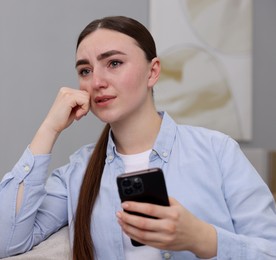 Photo of Depressed woman calling hotline for mental health help on sofa at home. Space for text