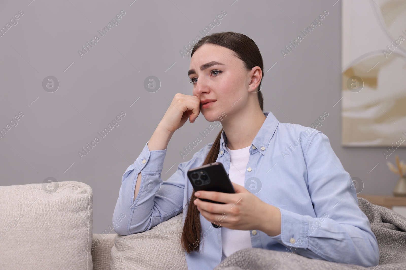 Photo of Depressed woman calling hotline for mental health help on sofa at home. Space for text