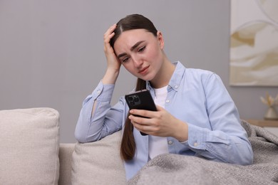 Photo of Depressed woman calling hotline for mental health help on sofa at home