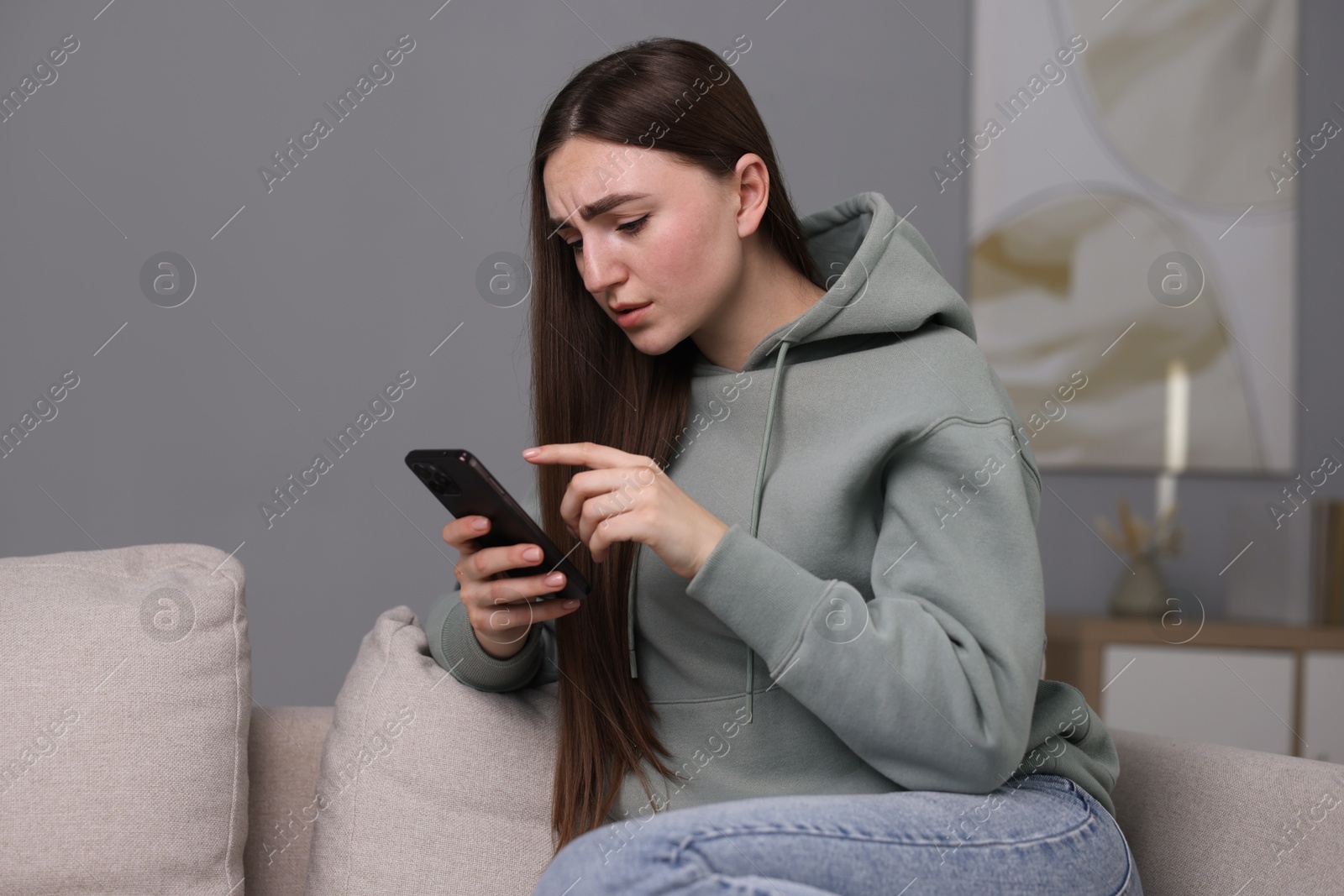 Photo of Depressed woman calling hotline for mental health help on sofa at home