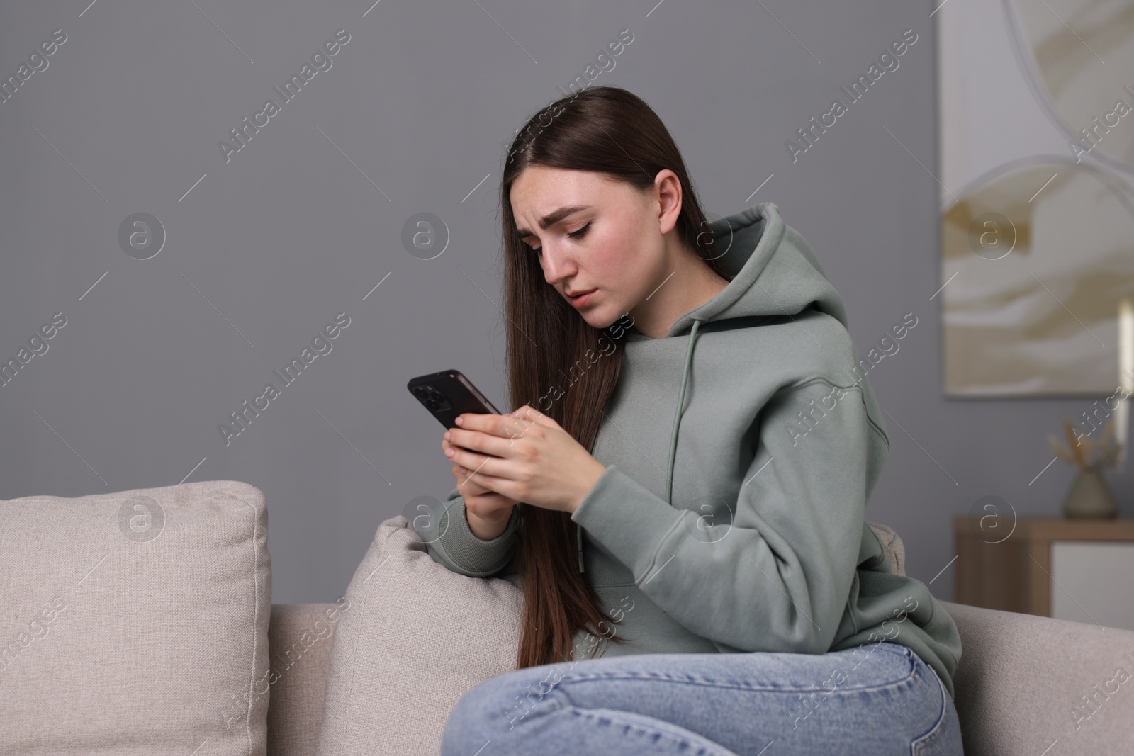 Photo of Depressed woman calling hotline for mental health help on sofa at home