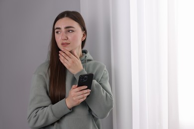 Photo of Desperate woman calling hotline for mental health help near window at home. Space for text