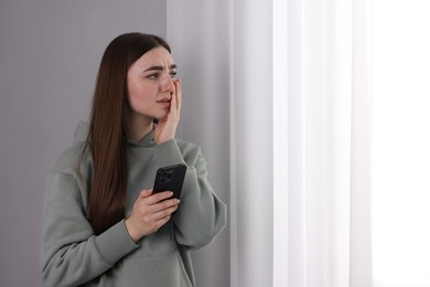 Photo of Desperate woman calling hotline for mental health help near window at home. Space for text