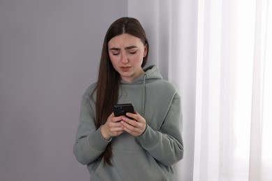 Photo of Desperate woman calling hotline for mental health help near window at home