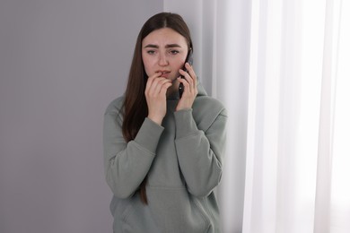 Photo of Desperate woman calling hotline for mental health help near window at home