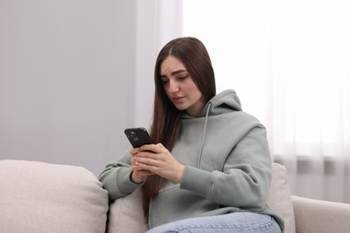 Photo of Depressed woman calling hotline for mental health help on sofa at home