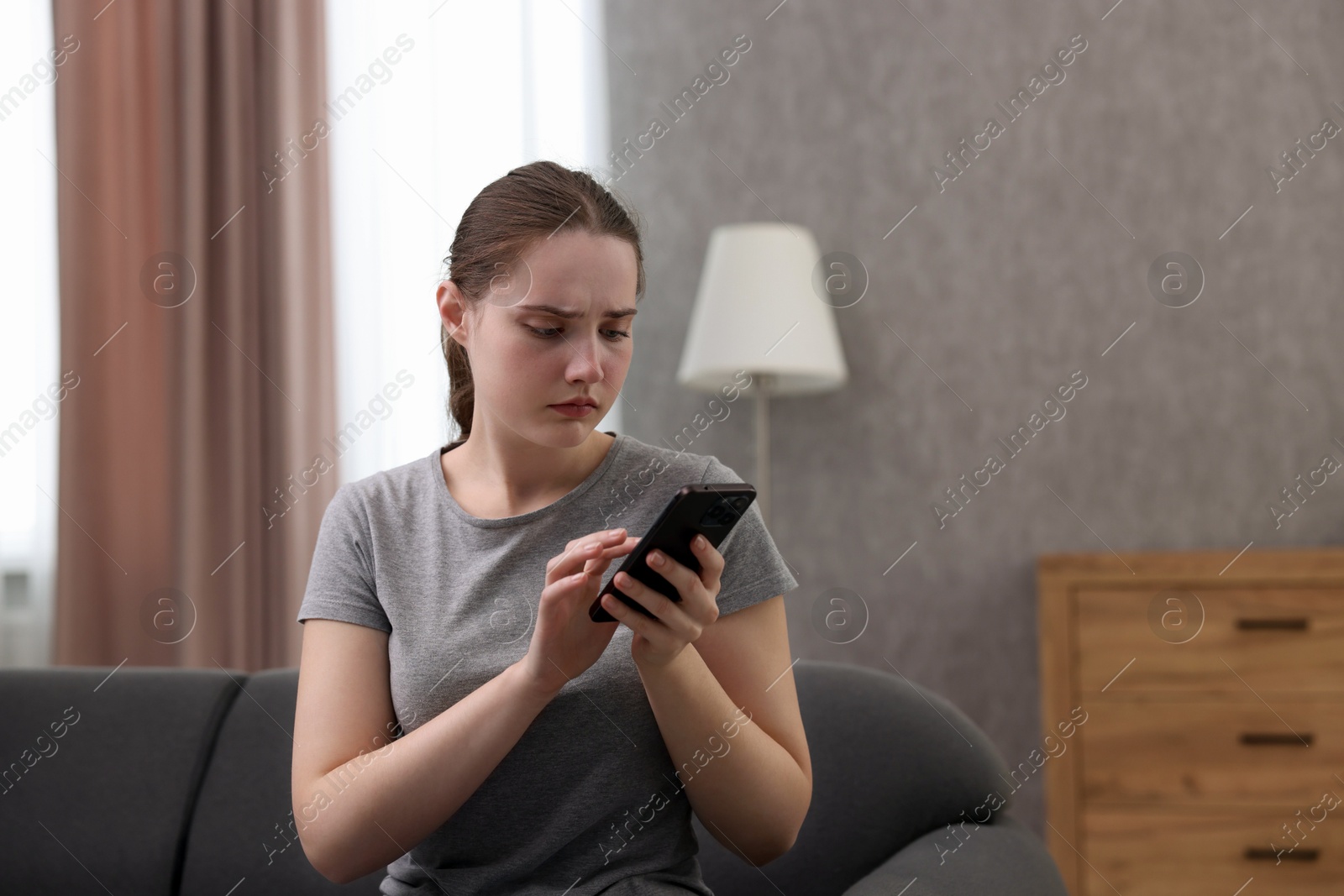 Photo of Depressed woman calling hotline for mental health help on sofa at home. Space for text