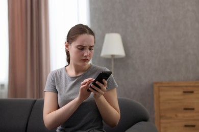 Photo of Depressed woman calling hotline for mental health help on sofa at home. Space for text