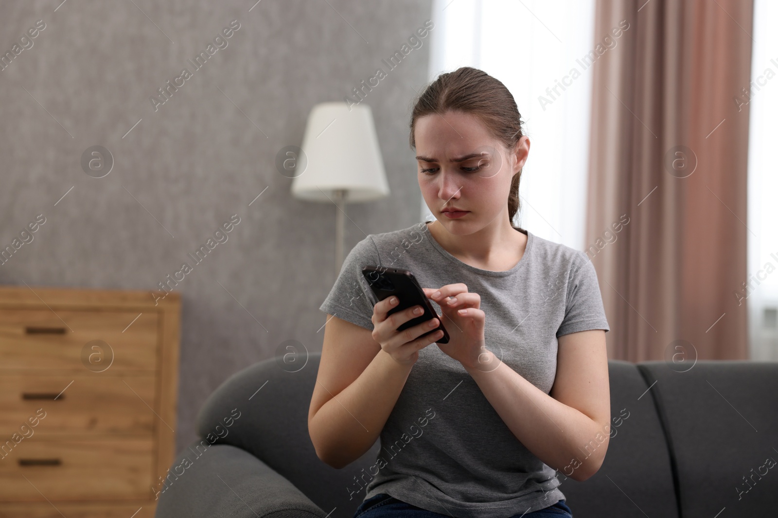 Photo of Depressed woman calling hotline for mental health help on sofa at home. Space for text