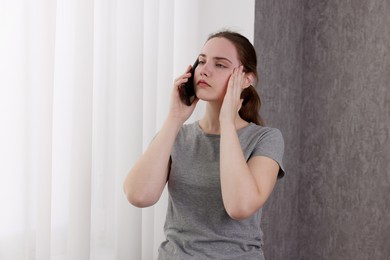 Photo of Stressed woman calling hotline for mental health help near window at home. Space for text