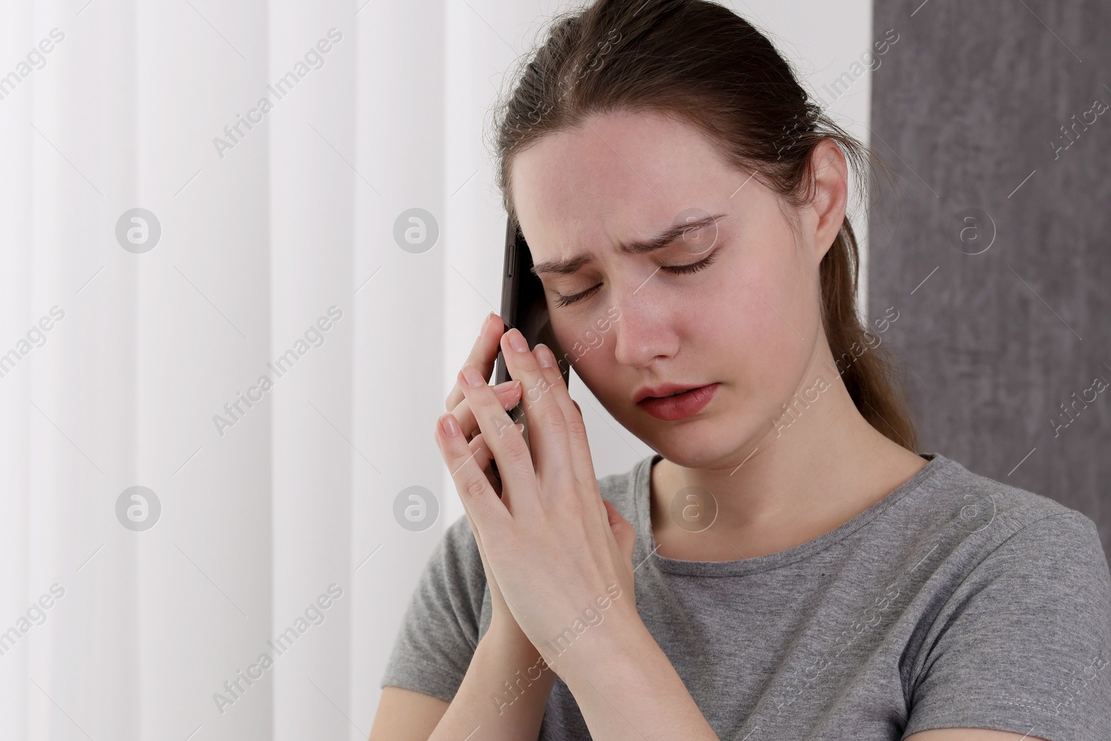 Photo of Stressed woman calling hotline for mental health help near window at home. Space for text