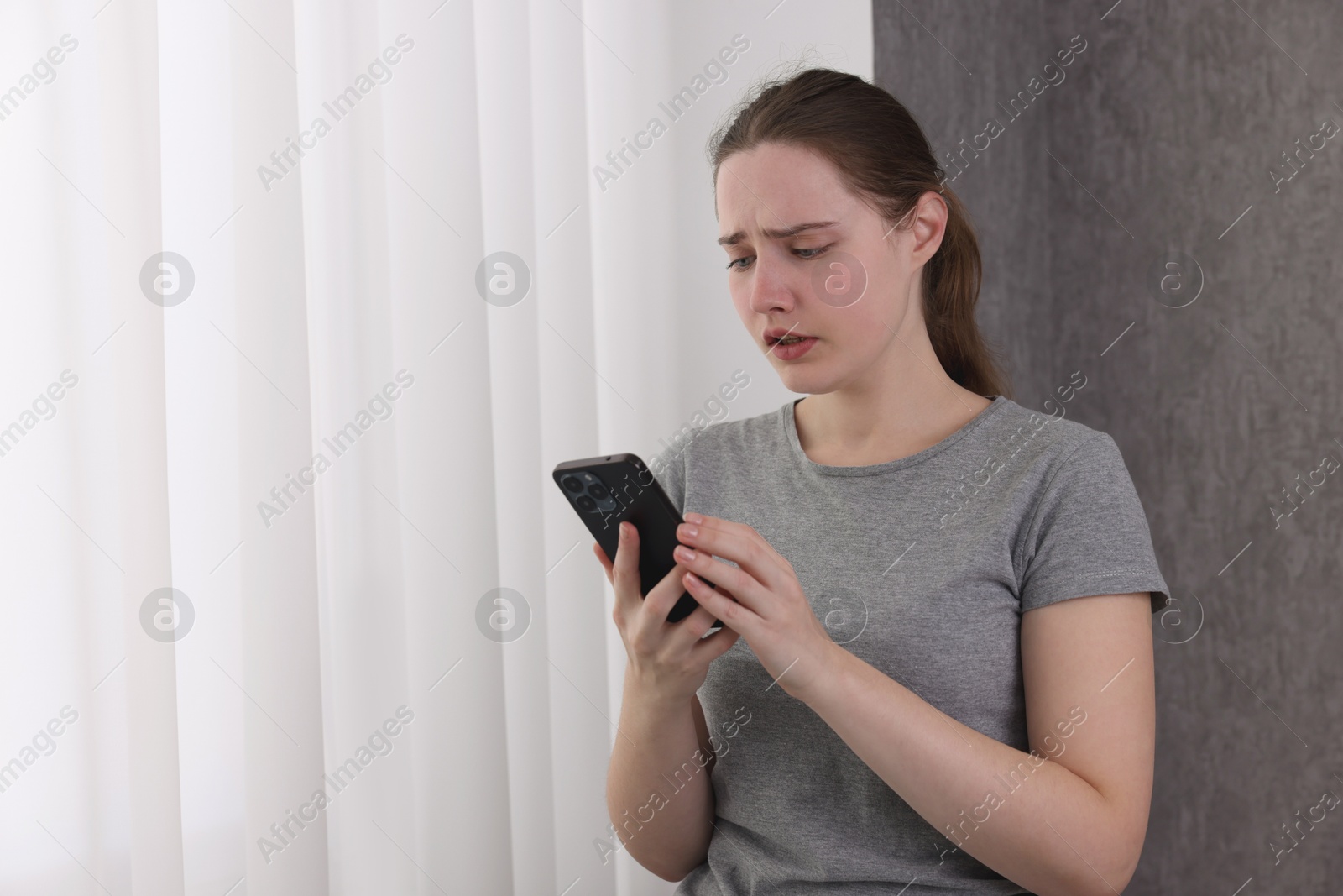 Photo of Stressed woman calling hotline for mental health help near window at home. Space for text