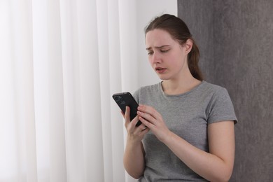 Photo of Stressed woman calling hotline for mental health help near window at home. Space for text